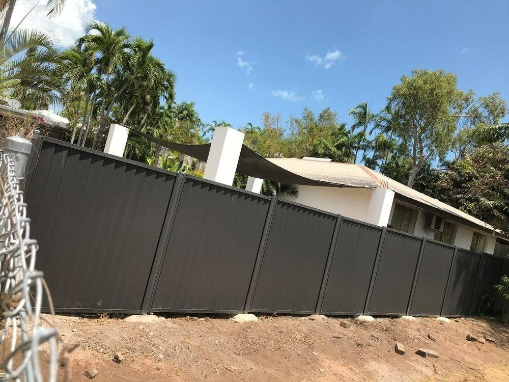 A Black Fence Is Surrounding A House On A Hill — Rabbo's Fencing Services In Pinelands, NT