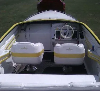 The inside of a boat with two seats and a steering wheel.
