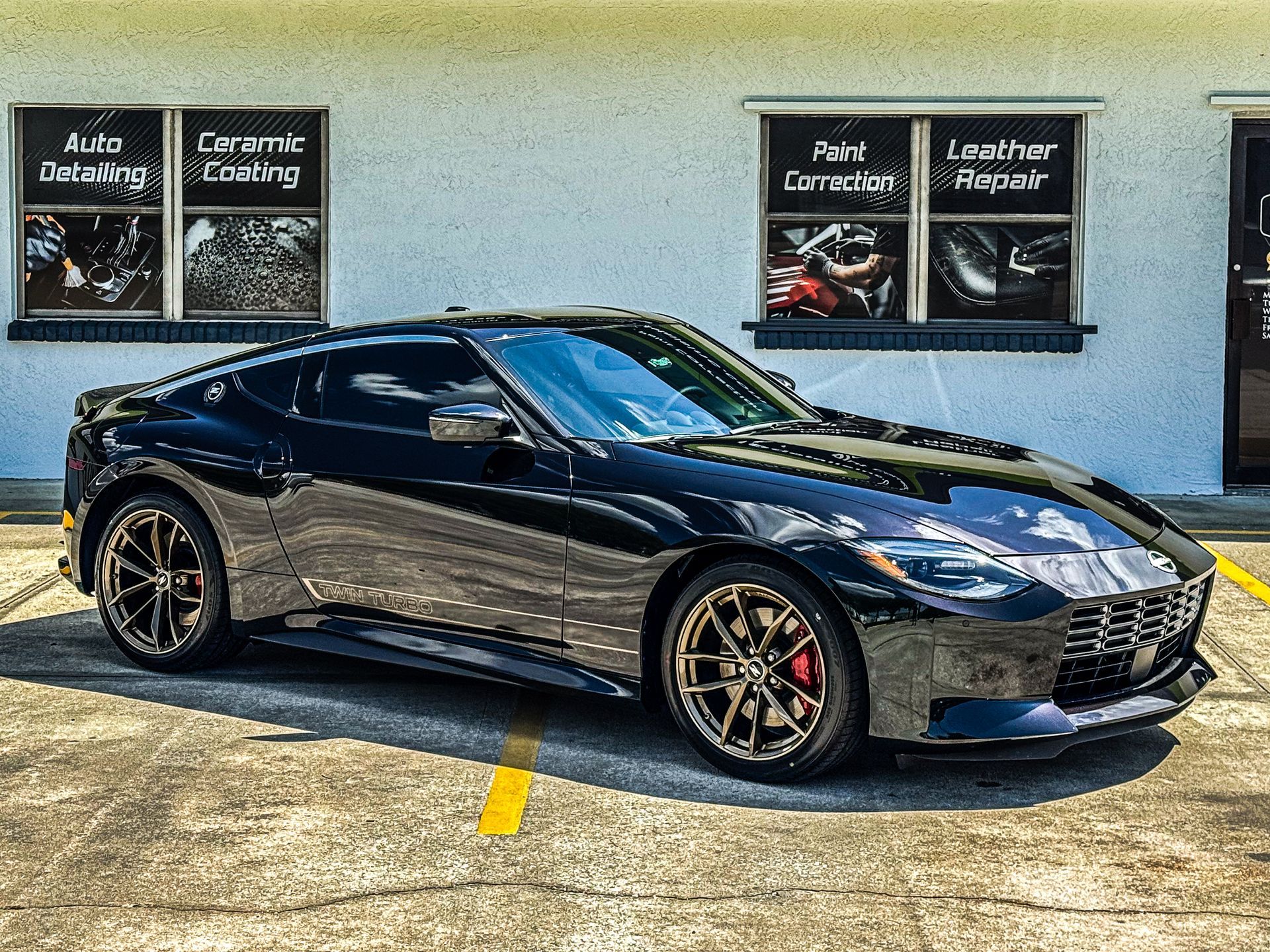 Black sports coupe parked indoors under garage-style wall signs.