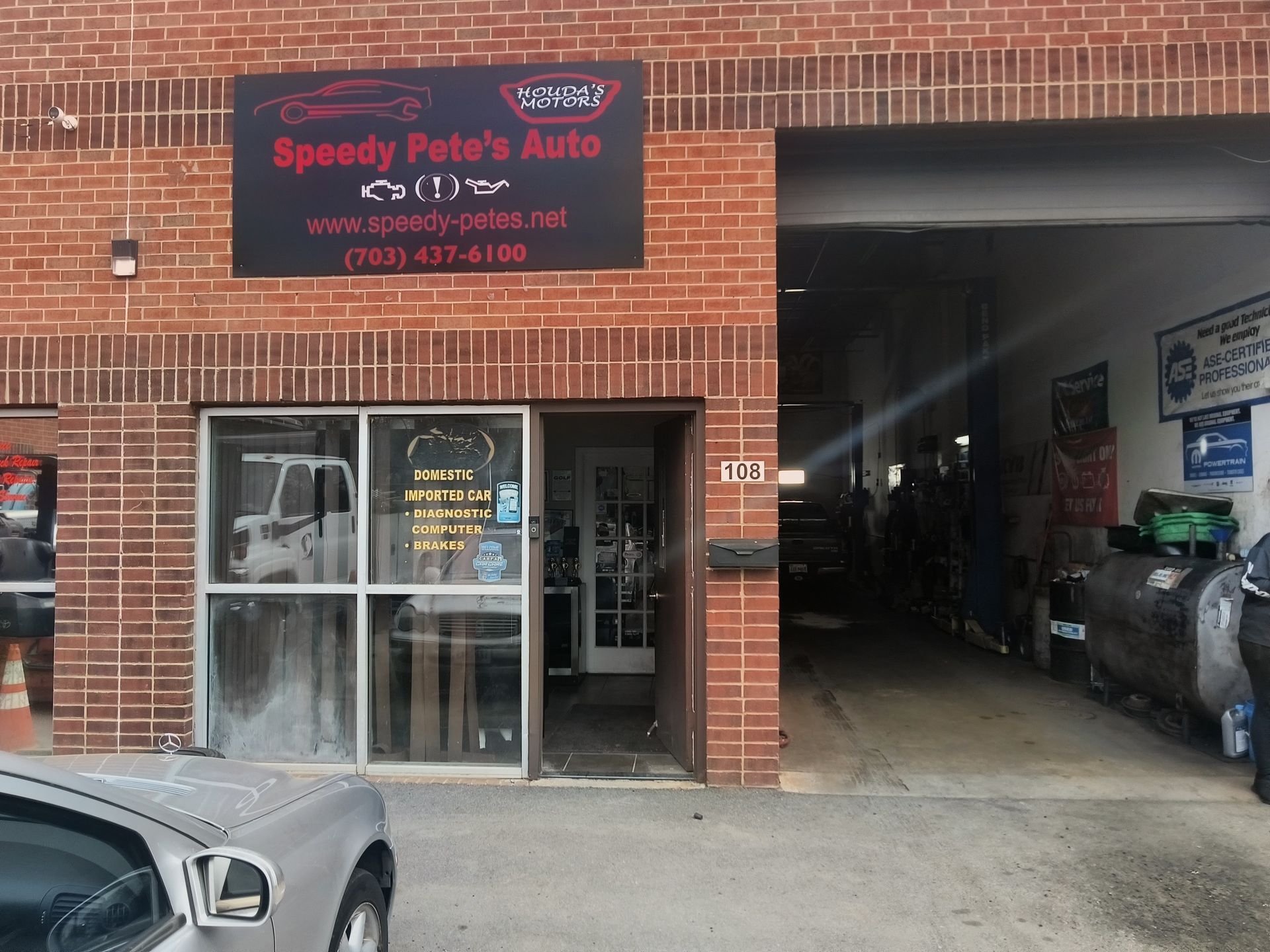 Auto repair shop storefront with open garage bay and red sign on a brick building