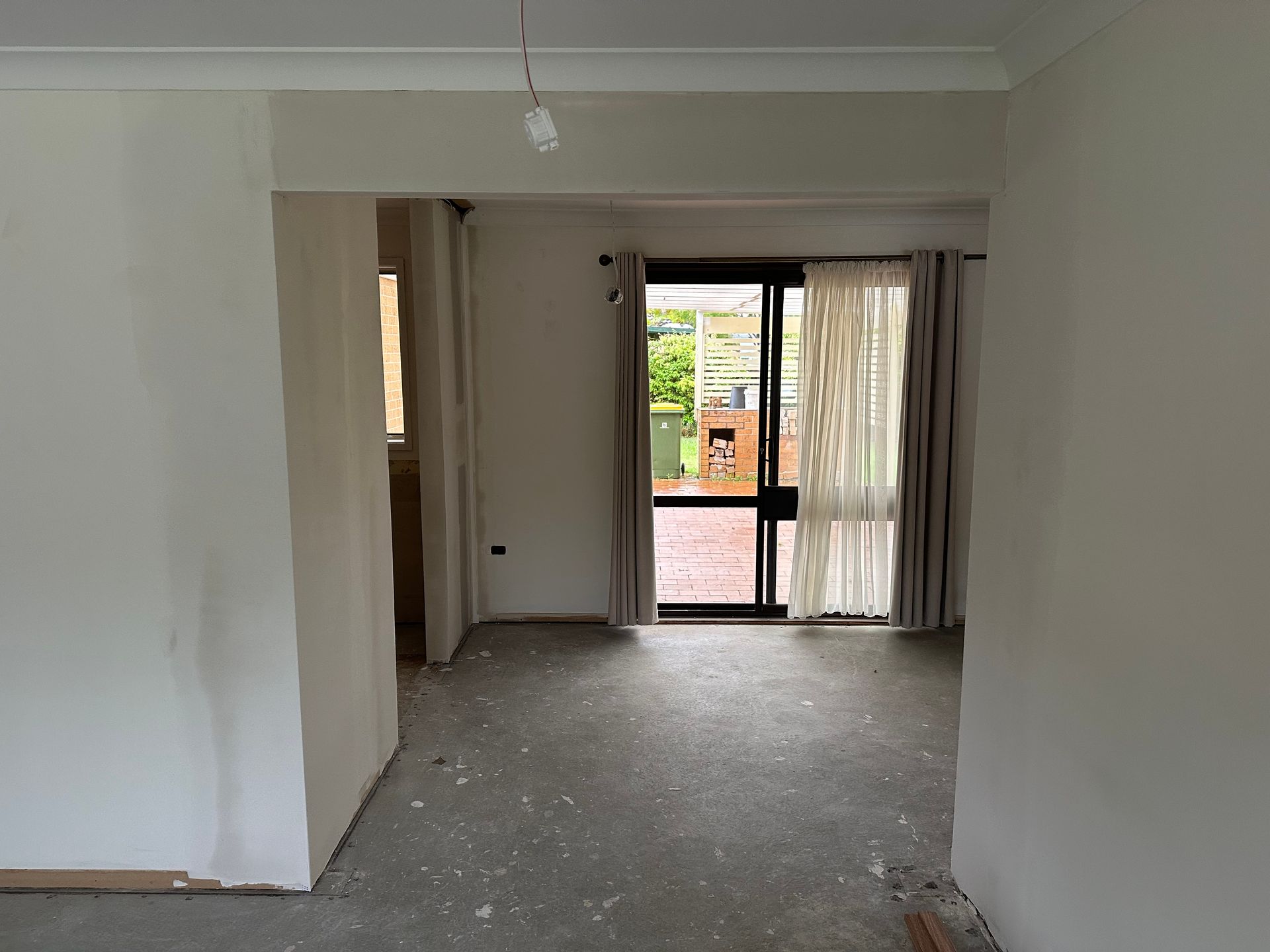 Empty unfinished living room with gray carpet, white walls, and sliding glass doors to a balcony.