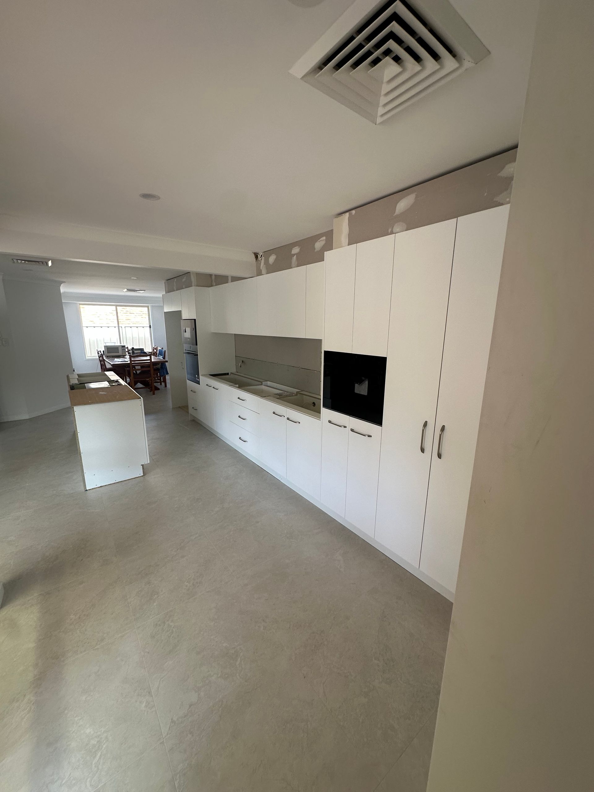 Bright modern hallway with white cabinets, built-in TV, and a distant living area.