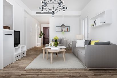 Bright modern living room with gray sofa, white rug, round coffee table, and kitchen in the background