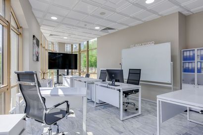 Bright modern office with desks, chairs, computers, and a large whiteboard.