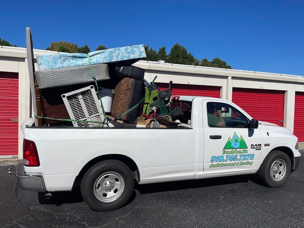 White pickup truck loaded with items in front of storage units; sunny day.