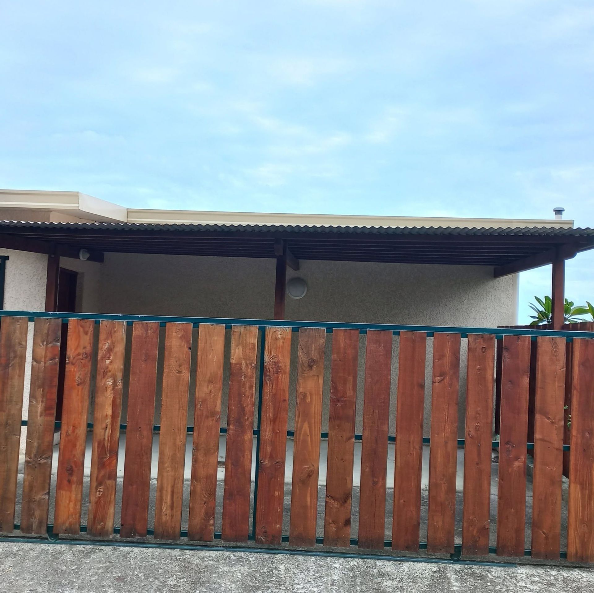 brown vertical wood-slat fence under a carport roof