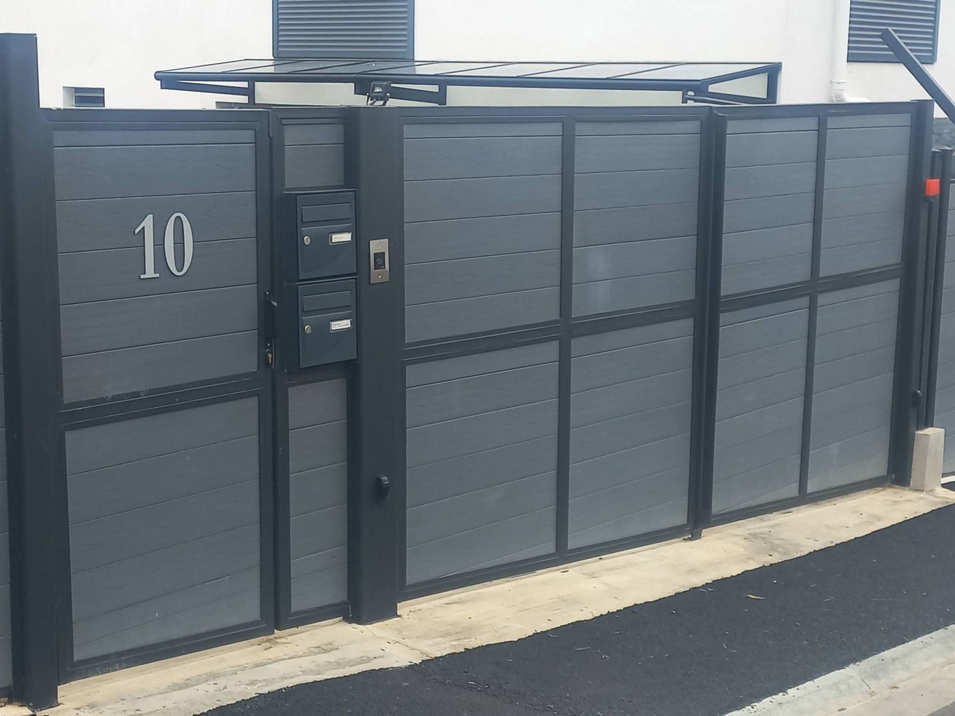 dark gray aluminum sliding gate with house number 