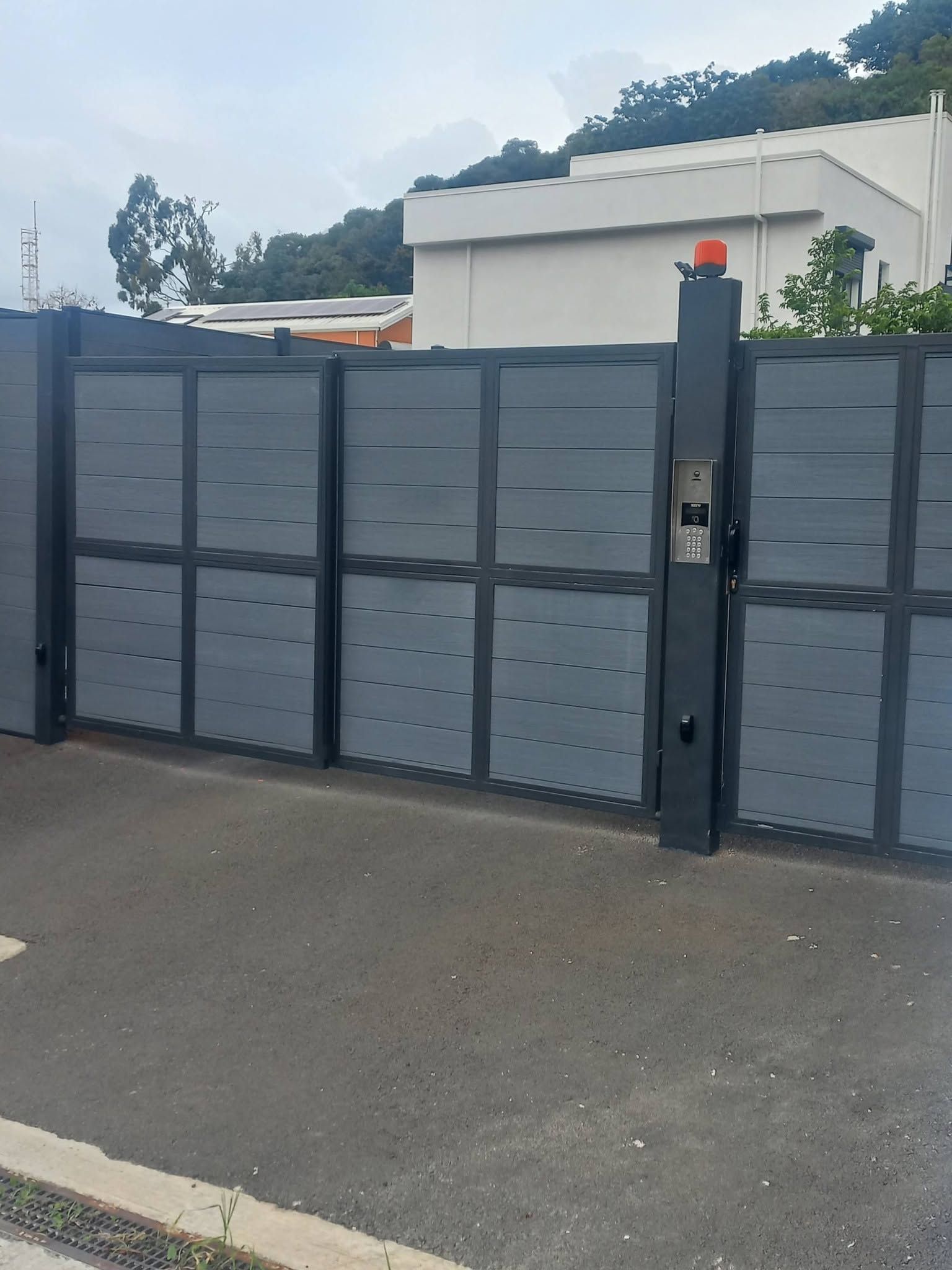 dark gray solid gate panel with a post, driveway visible