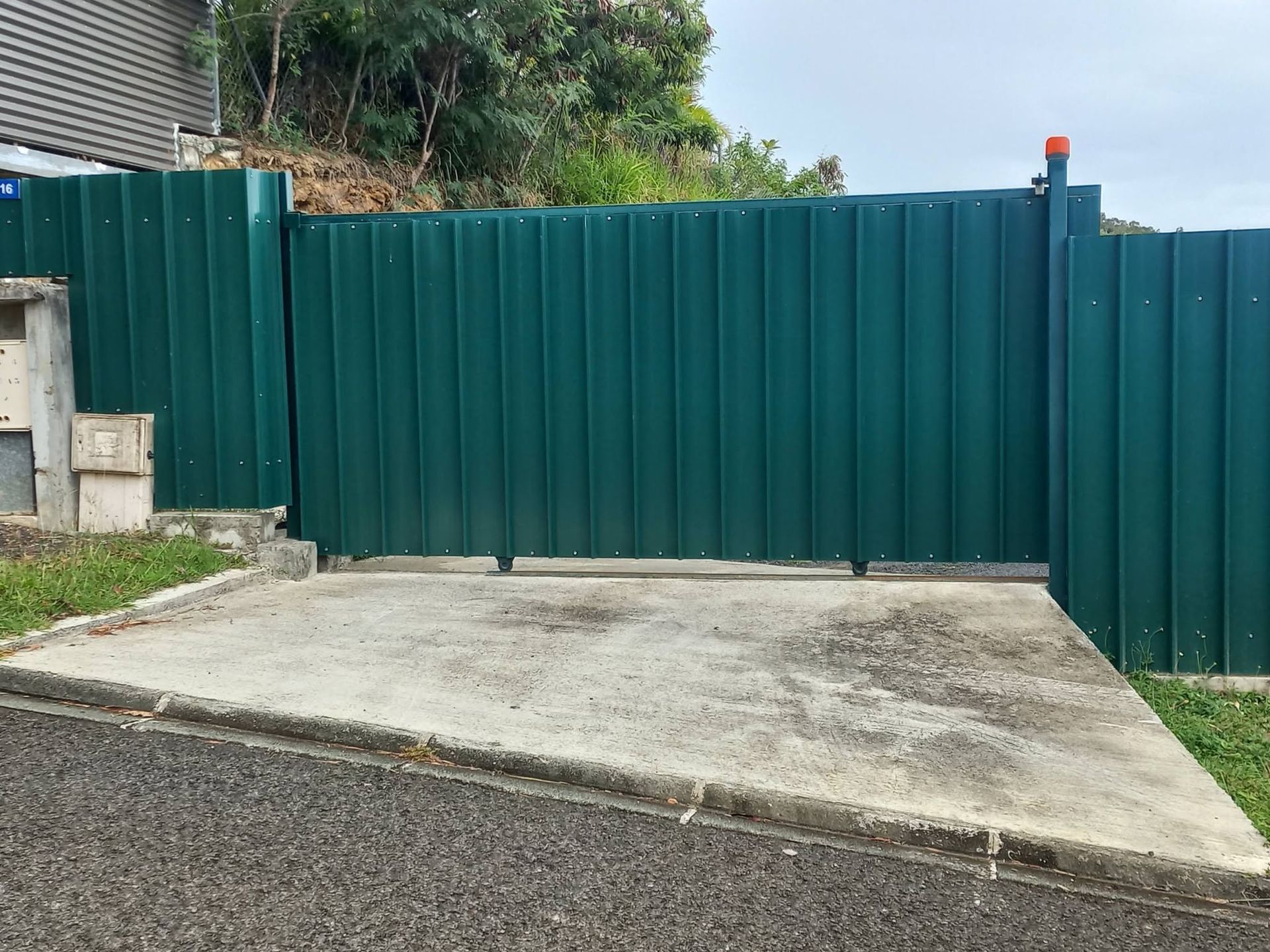 Réalisateal corrugated-metal fence along a paved drivewaytion
