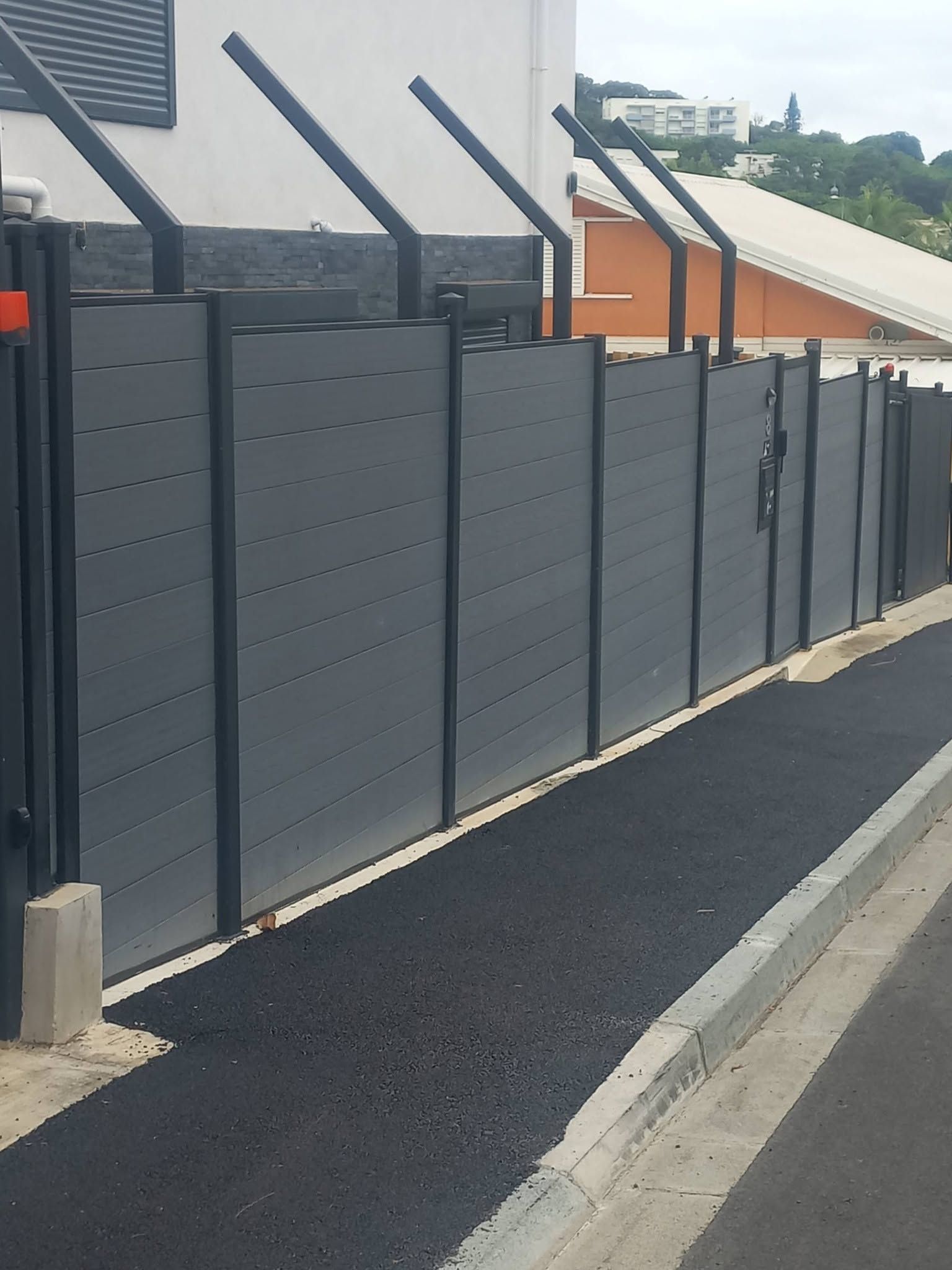 dark gray fence panels along a paved walkway near a pool