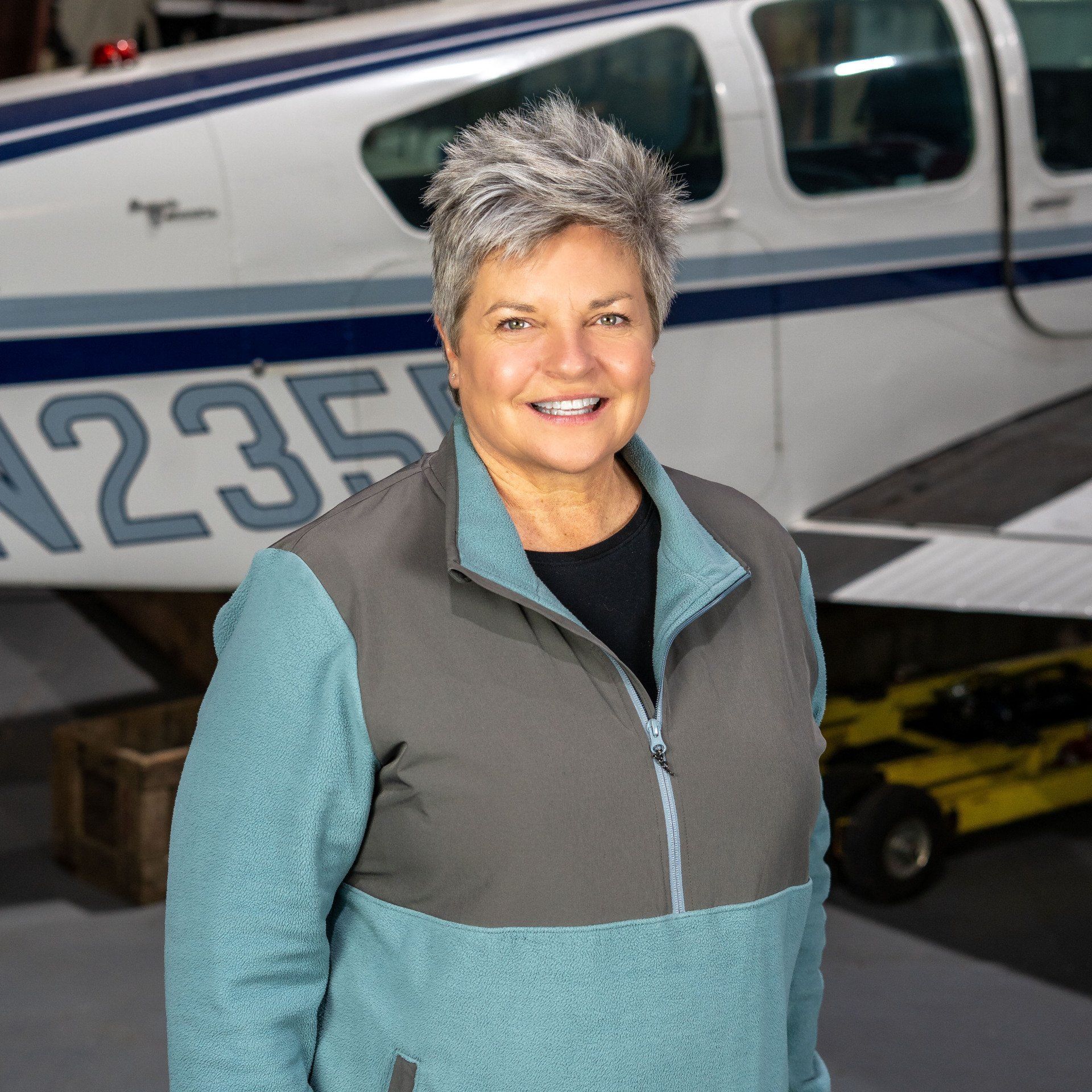 A woman is standing in front of a plane with the number 235 on it