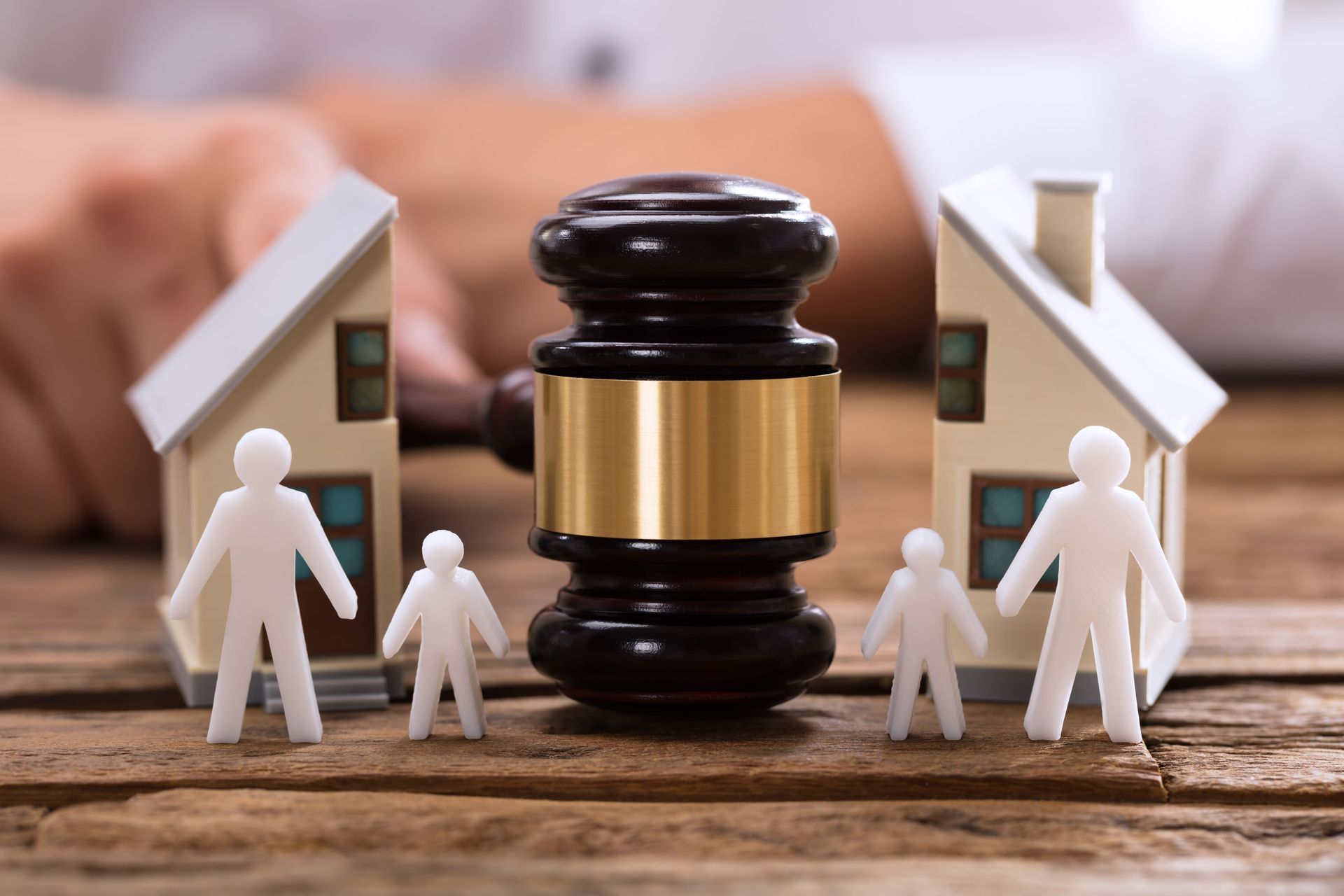 Court gavel between two house models with paper figures, symbolizing a property dispute or legal ruling