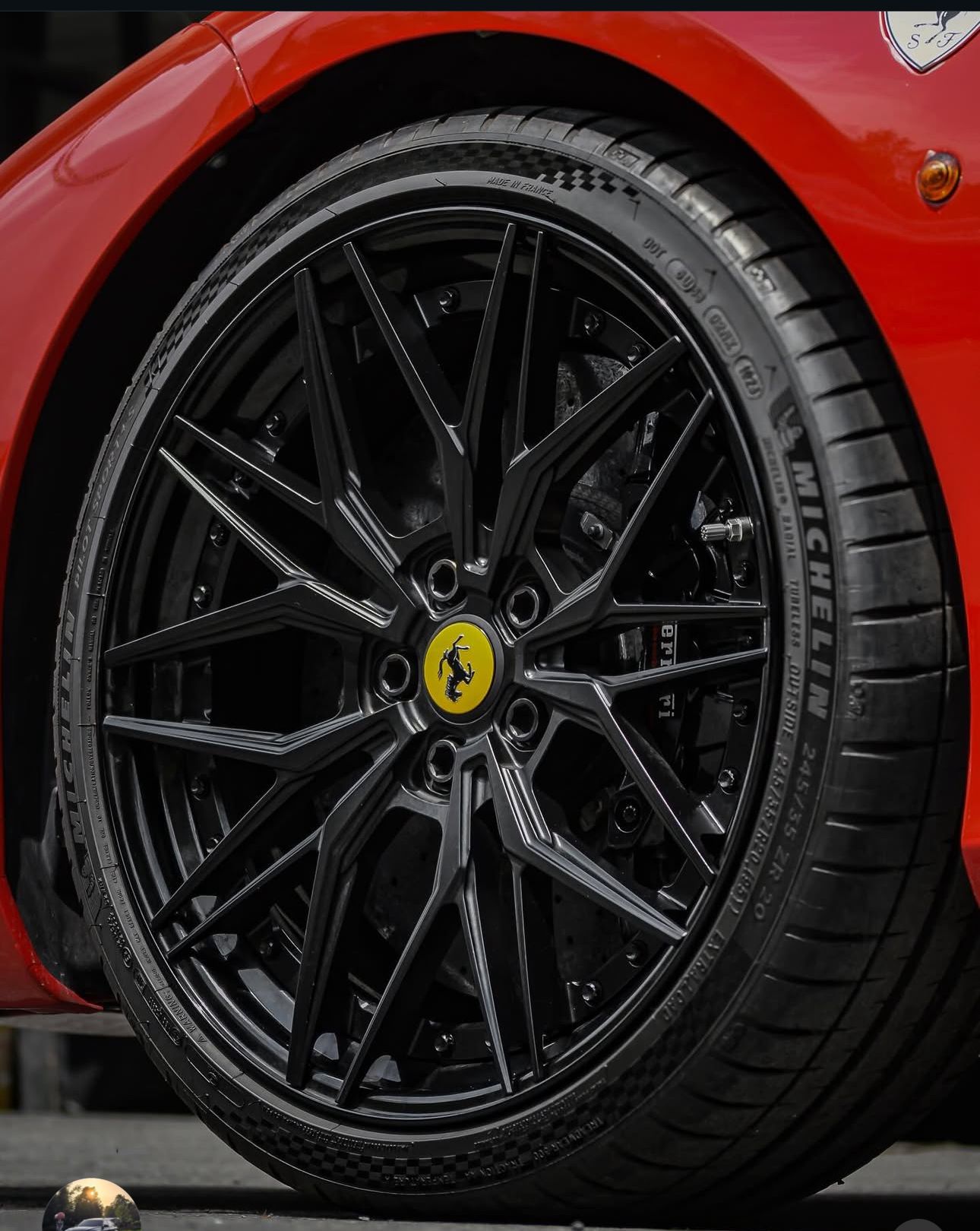 Black wheel with Ferrari logo on red car. | Honesty Automotive Repairs