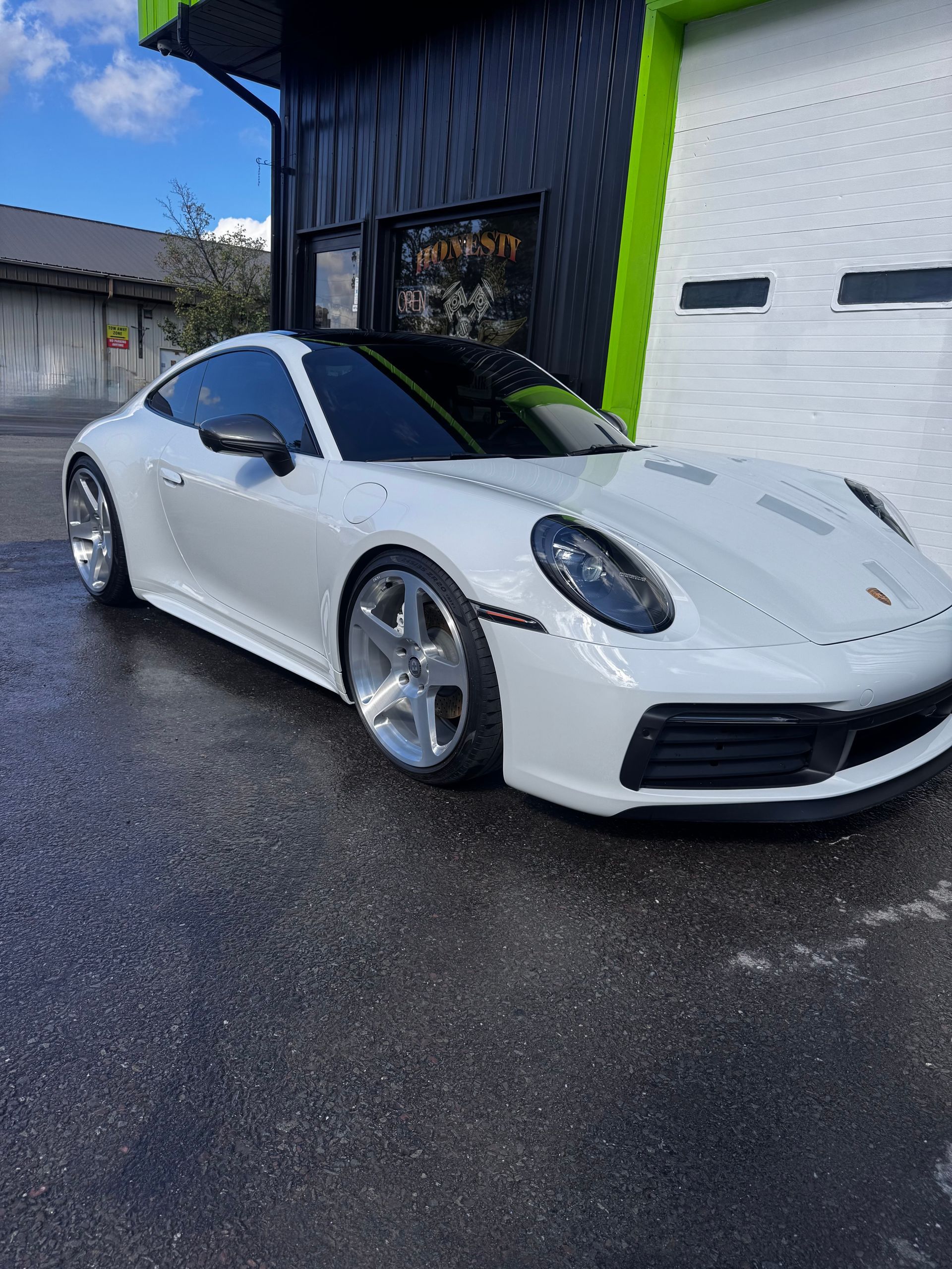 White Porsche 911 parked outside a building with tinted windows on a sunny day. | Honesty Automotive Repairs