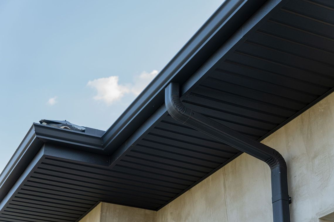 Modern house roof with dark gutters against a blue sky