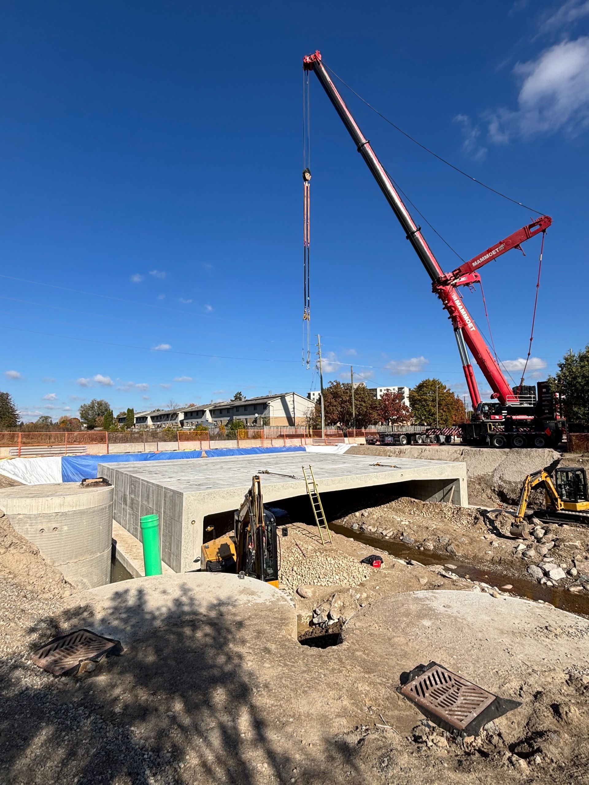 A very wide shot of culverts being installed under a road.