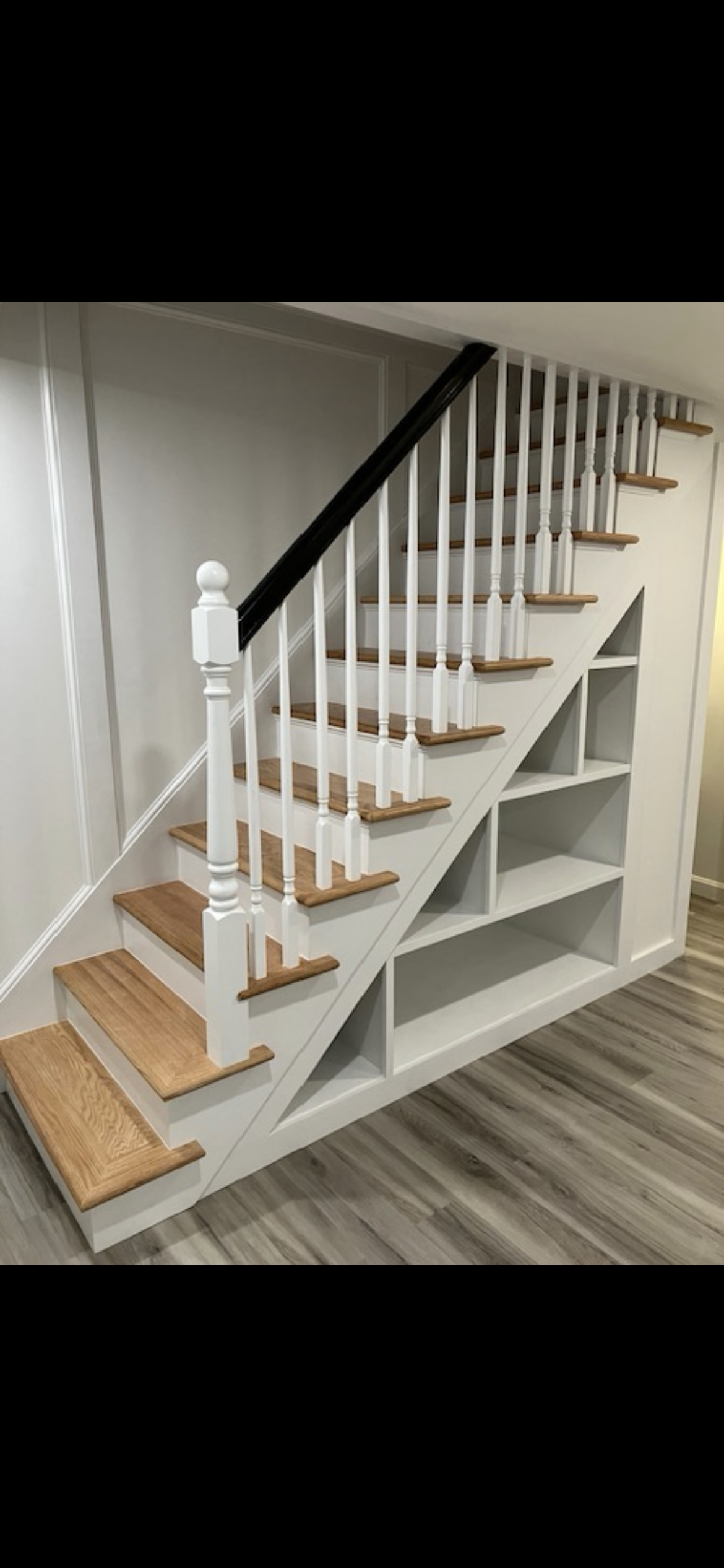 A staircase with wooden steps and shelves underneath it.