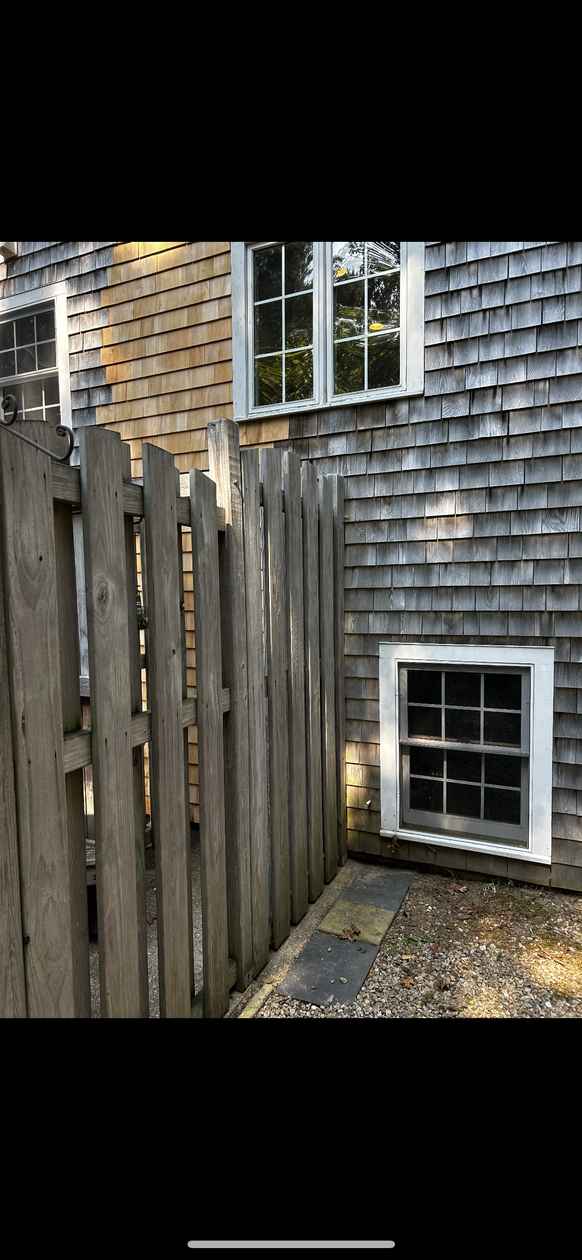 A wooden fence is in front of a house with a window.