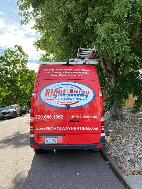 Four red service vans parked in front of a stone-faced building with the 
