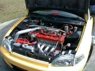 Open car hood showing a red engine and polished intake in a yellow car Open car hood showing a red engine and polished intake in a yellow car