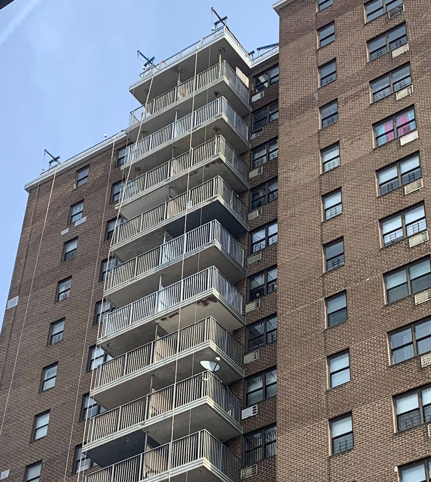 A tall brick building with many balconies and windows.