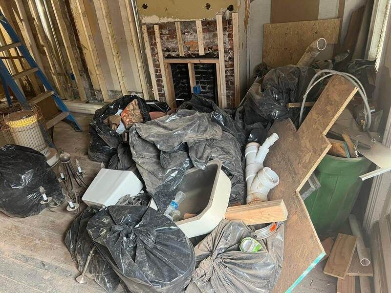 a man is carrying a bag of trash next to a garbage truck .