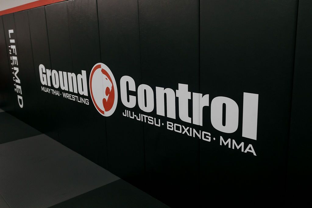 Ground Control martial arts gym wall with black padding and white logo text for jiu-jitsu, boxing, and MMA