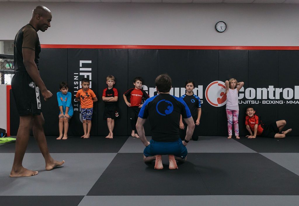 Martial arts class with instructor kneeling before students in a training gym