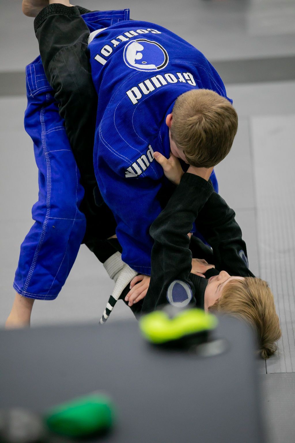 Blue-clad martial artist grappling an opponent on a mat during a judo match