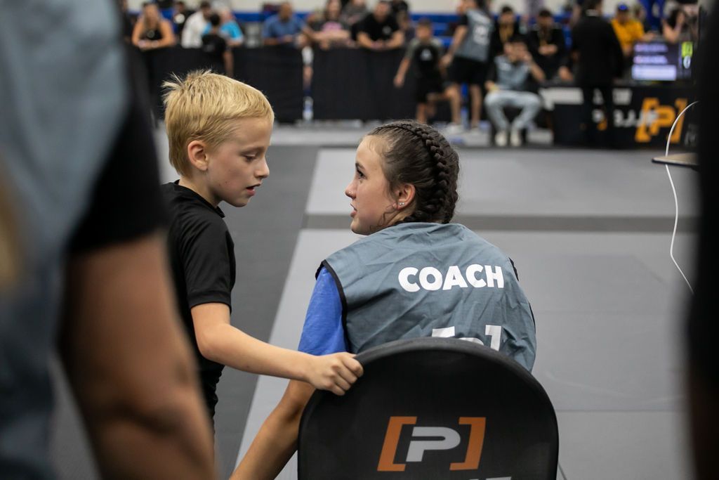 Young wrestler talking with coach at mat side during a youth wrestling match