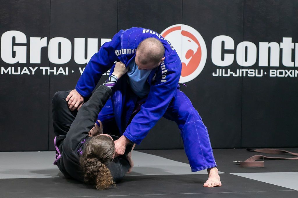 Two Brazilian jiu-jitsu practitioners grappling on a mat during a martial arts match.