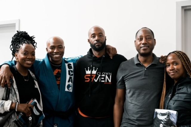 Group of five people, all smiling, posing for a photo indoors.