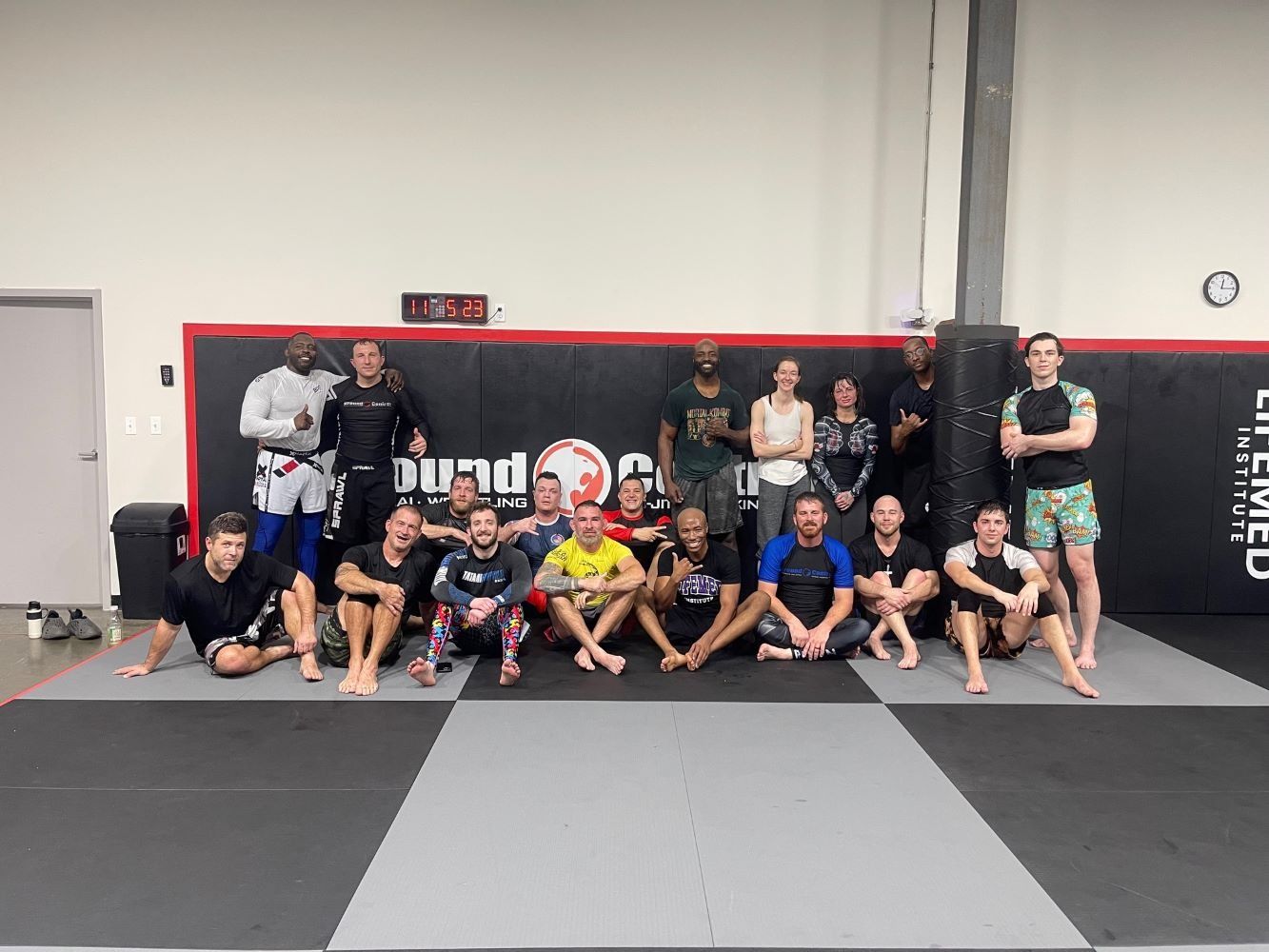 Group of people in gym, posing on mats. People of diverse races and dressed in athletic attire.