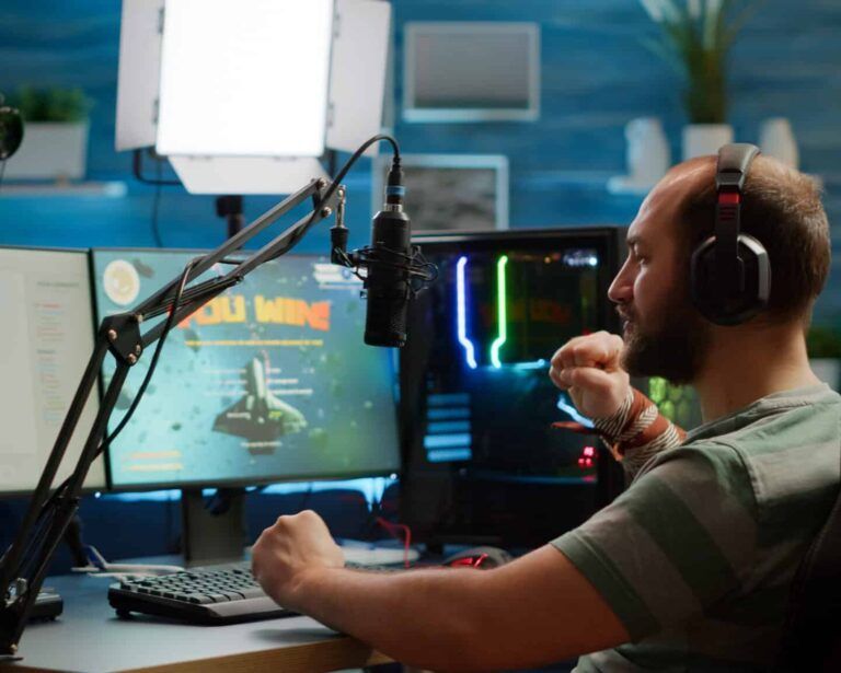 A streamer with headphones celebrating while looking at a screen displaying a 