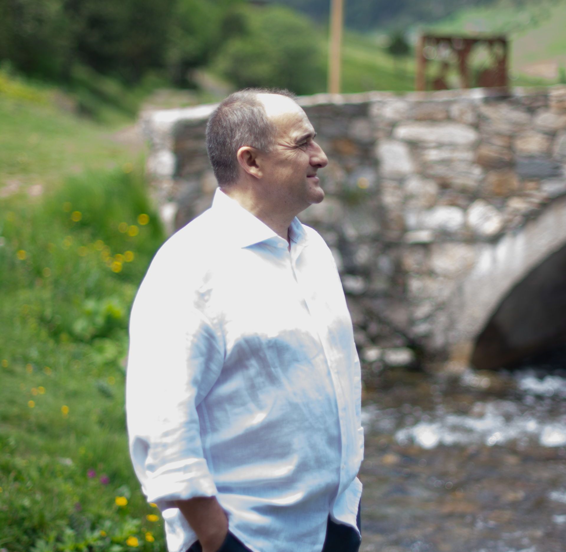 Un hombre con una camisa blanca está parado al lado de un río.