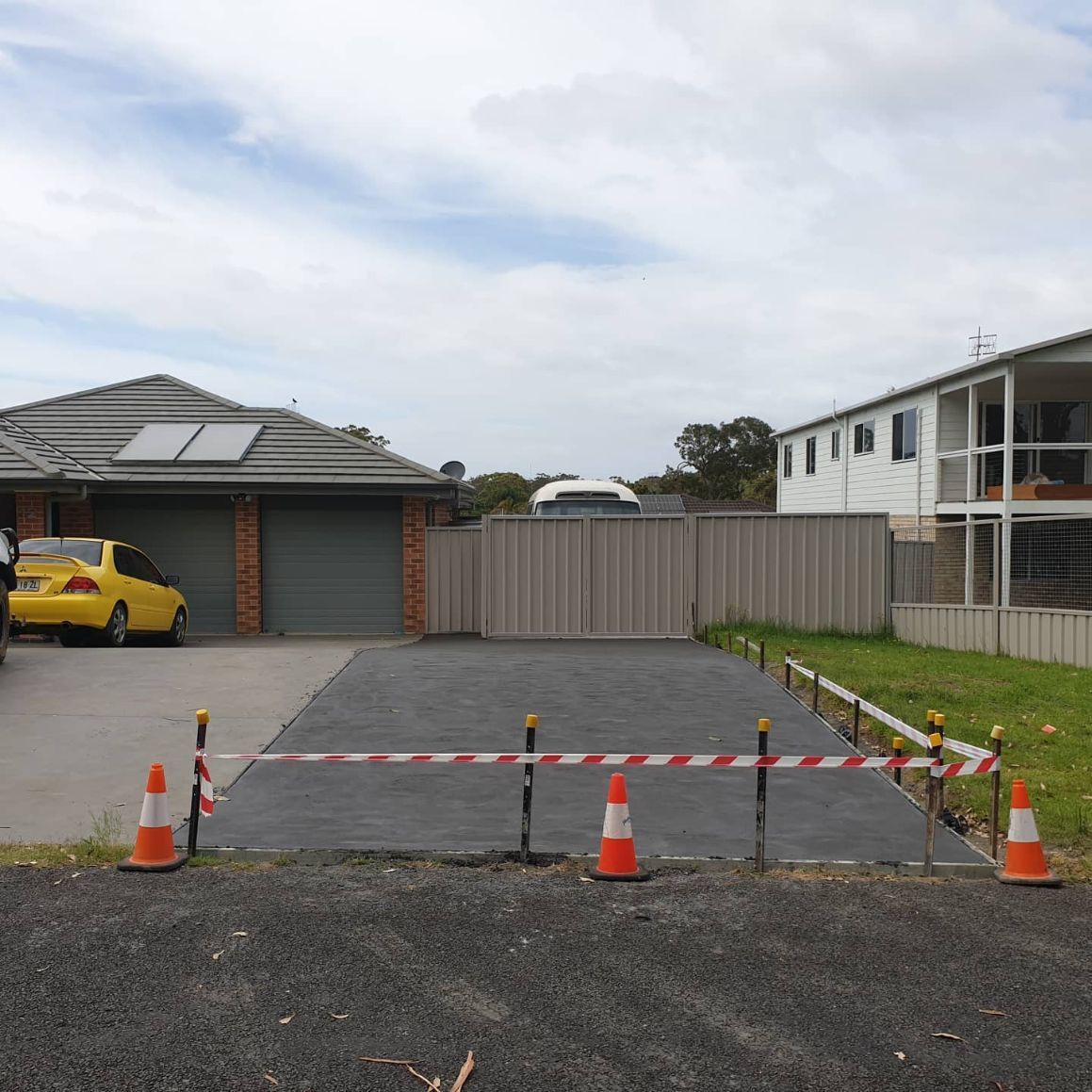 A Yellow Car Is Parked in The Driveway of A House — Turn It Crete in St Georges Basin, NSW
