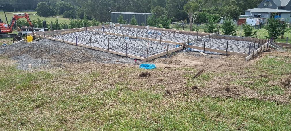 A Construction Site In A Grassy Field With A House In The Background — Turn It Crete in St Georges Basin, NSW
