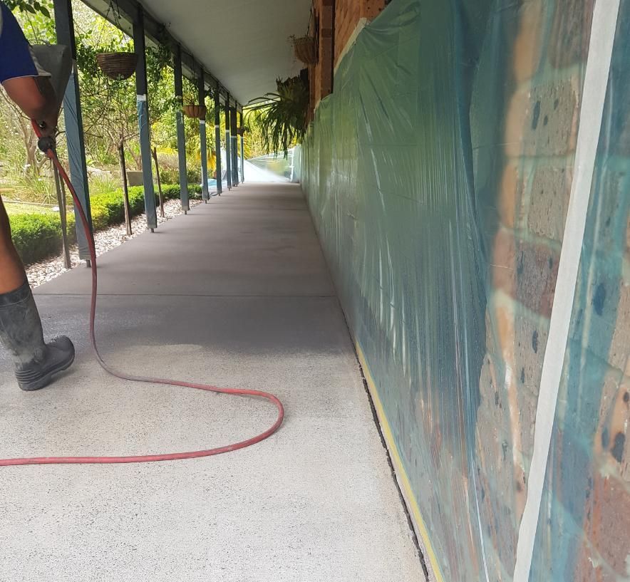 A Man Is Using A Vacuum Cleaner To Clean A Concrete Walkway — Turn It Crete in St Georges Basin, NSW