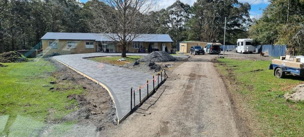 A Dirt Road Leading To A House In The Middle Of A Grassy Field — Turn It Crete in St Georges Basin, NSW