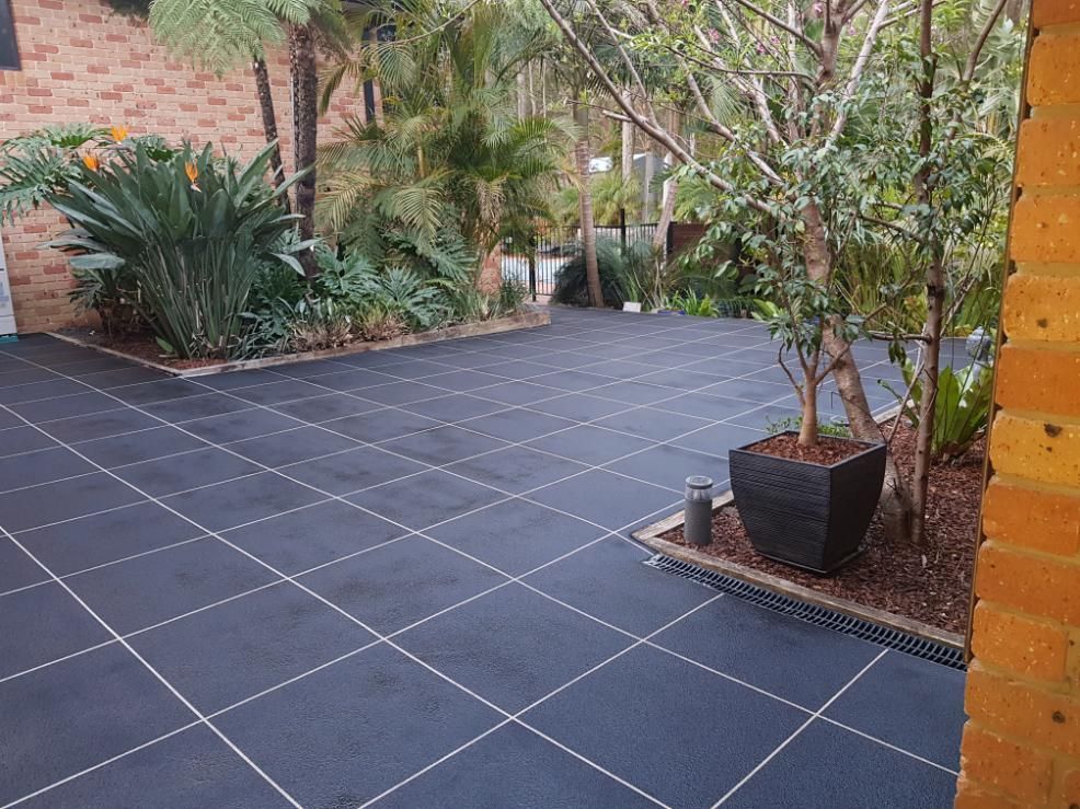 A Black Tiled Driveway With A Potted Plant In The Middle Of It — Turn It Crete in St Georges Basin, NSW