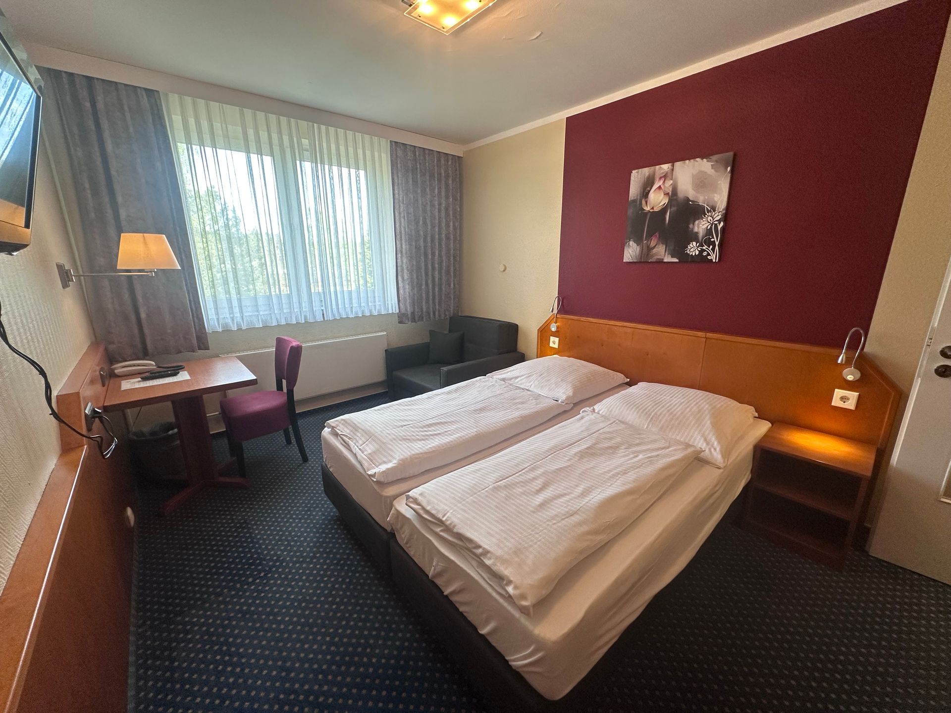 Ein Hotelzimmer mit zwei Betten und einem Fernseher an der Wand.