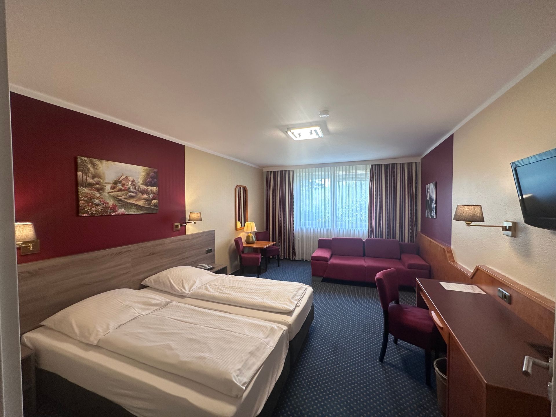 A hotel room with two beds , a couch , a desk and a television.