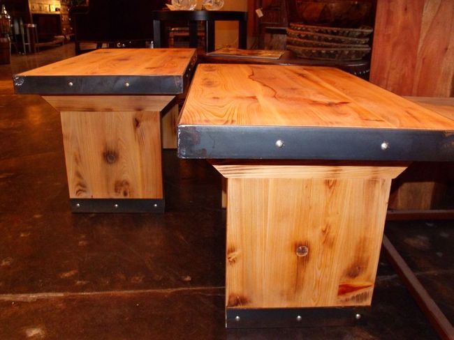 Two wooden tables with metal trim sit on a dark floor