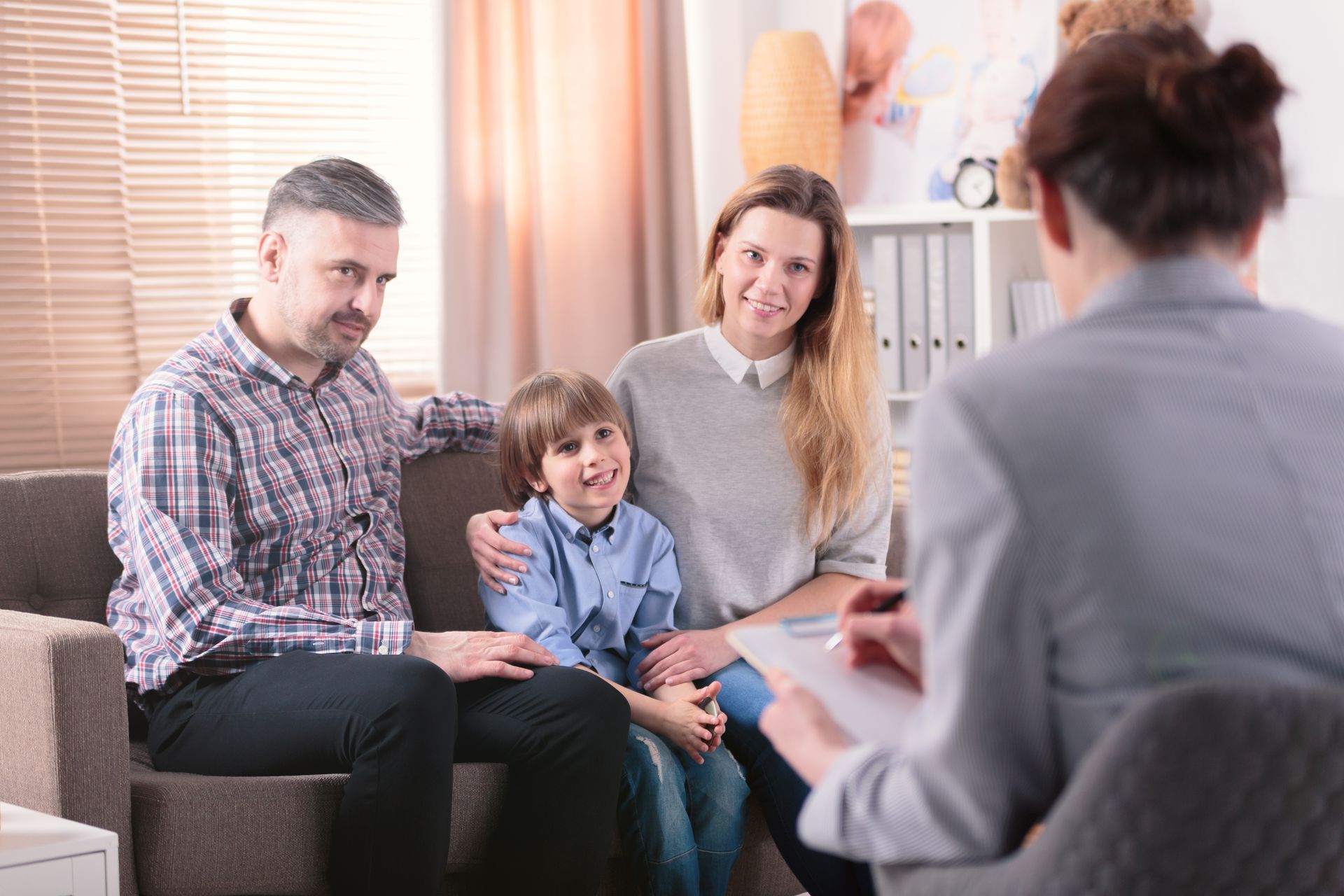 A family is sitting on a couch talking to a woman.