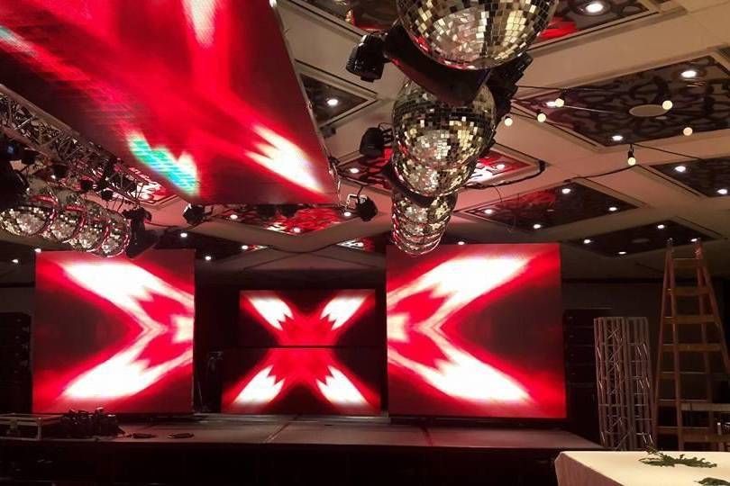 Espectáculo de luces rojas y blancas en el escenario con bolas de espejos colgando.