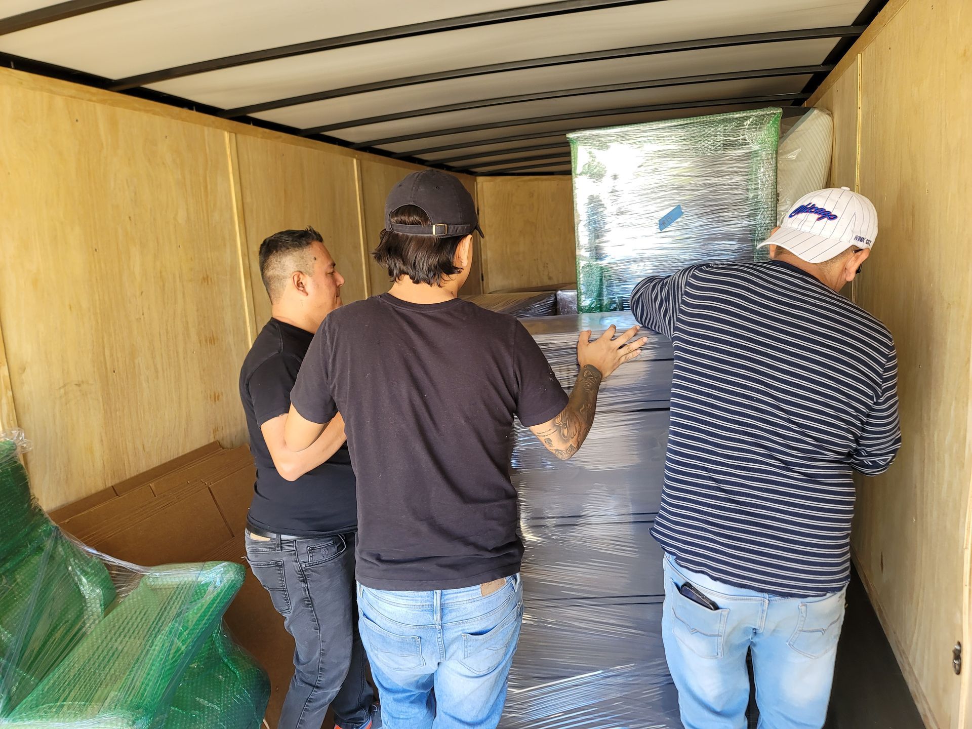 Three men are loading a large item into a truck.