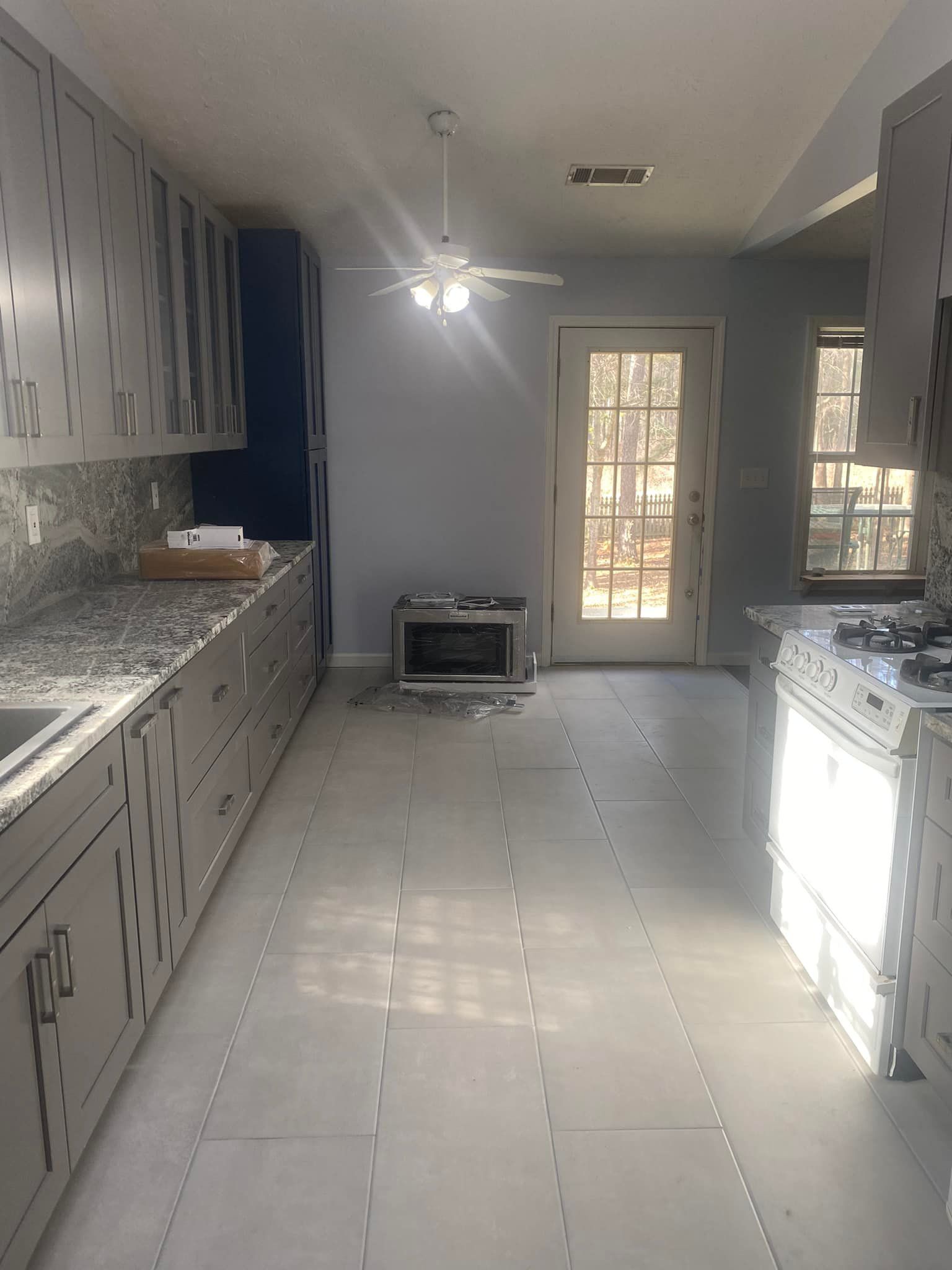 A kitchen with white cabinets and a ceiling fan