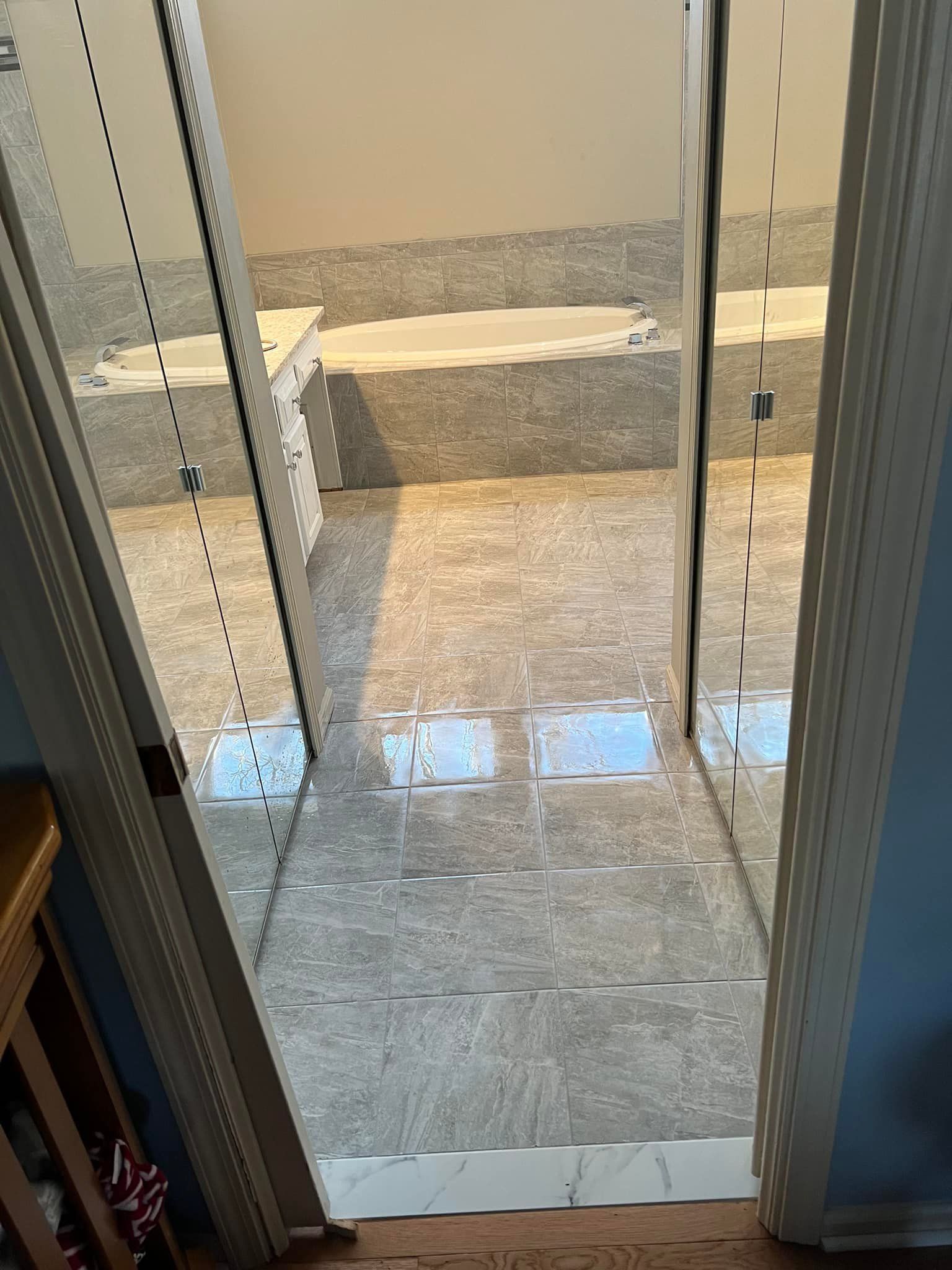 A bathroom with a bathtub and a large mirror.