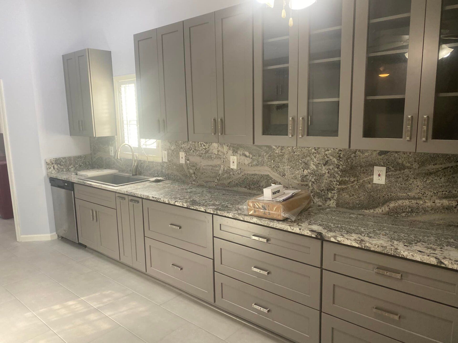 A kitchen with gray cabinets and granite counter tops