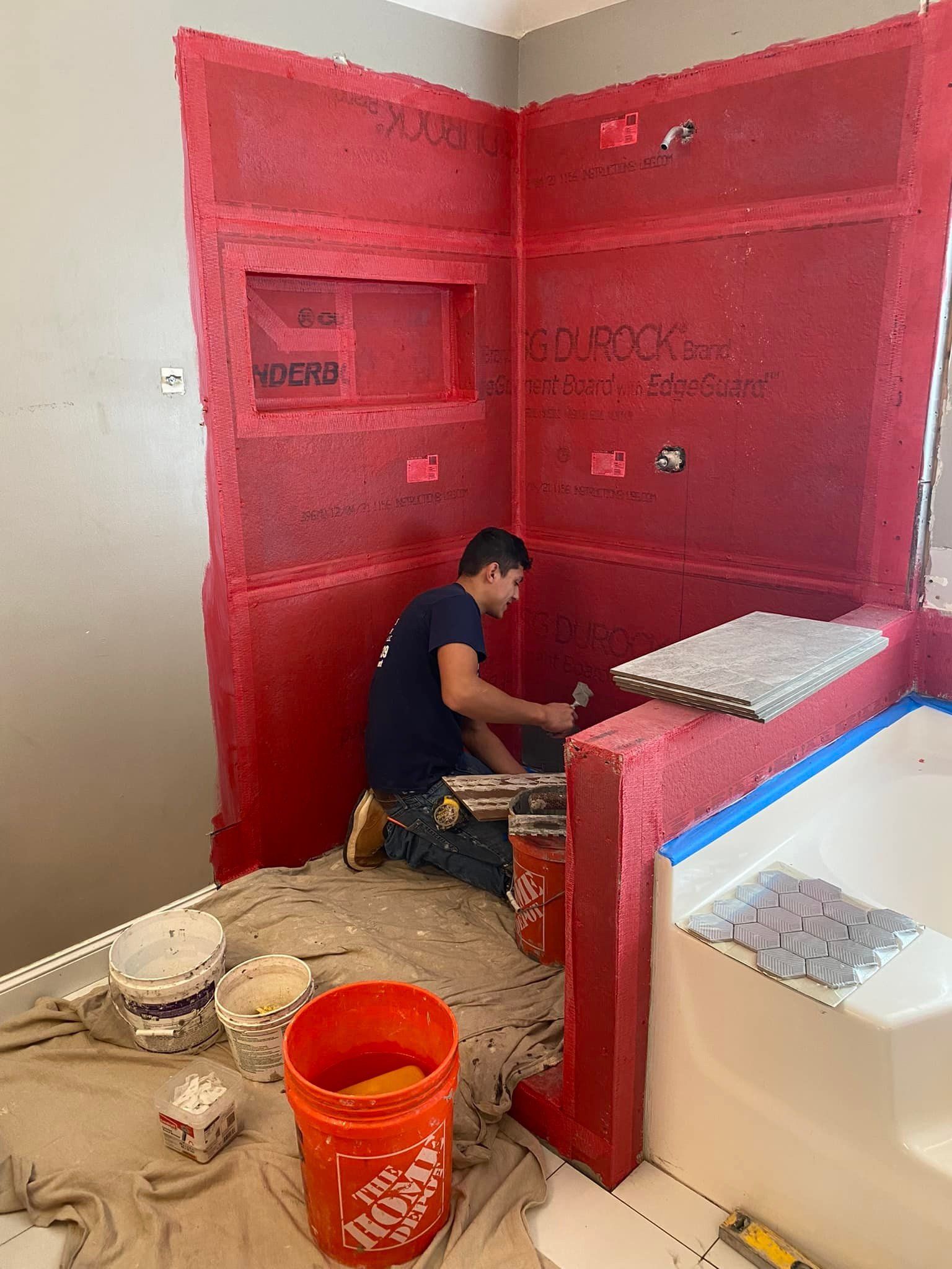 A man is kneeling on the floor in a bathroom.
